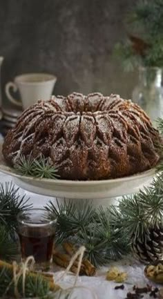 a bundt cake sitting on top of a white platter next to pine cones