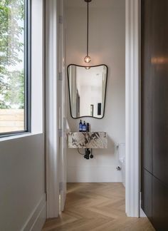 a bathroom with a mirror, sink and light hanging from it's side wall