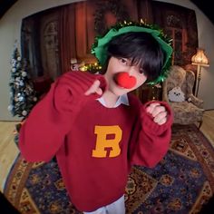 a young boy wearing a red sweater and clown nose