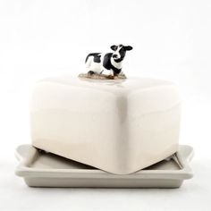 a small black and white cow figurine on top of a square shaped object