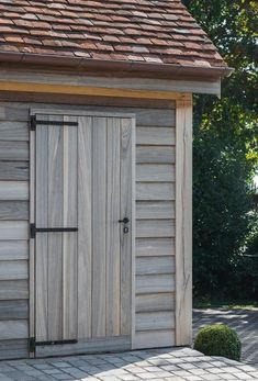 a small wooden building with a door on the outside and brick walkway in front of it