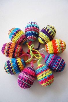 multicolored knitted balls are arranged in a circle on a white table top