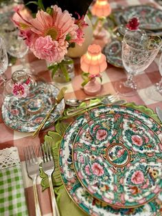 the table is set with plates, silverware and flowers