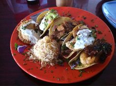 an orange plate topped with tacos and rice