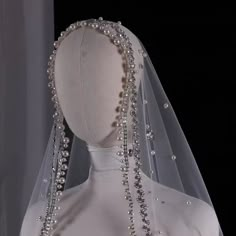 the back of a wedding dress with beaded veil and headpieces on display