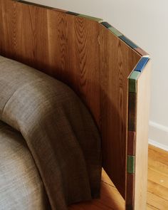 a bed with a wooden headboard and pillow on it's side in a room