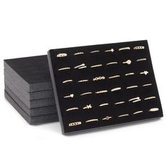 four black and gold jewelry boxes with different types of earrings in them on a white background