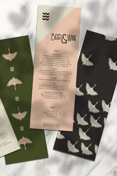 three different types of wine menus on a marble countertop with white and green paper