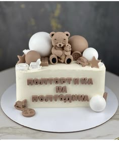 a teddy bear sitting on top of a cake with words written in white frosting