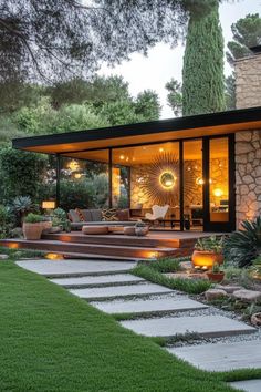 a modern house in the middle of a lush green yard with stone steps leading up to it