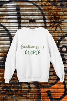 a white sweatshirt with the words enchanting cookie printed on it in green ink