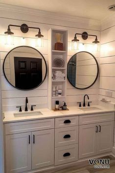 a bathroom with double sinks and two round mirrors on the wall, along with white cabinets