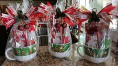 two coffee mugs with candy canes wrapped in cellophane and bows on them