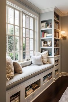 a window seat with bookshelves and pillows on it