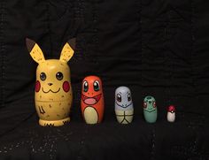 three different colored toy figures sitting next to each other on a black cloth covered surface