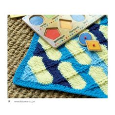 a crocheted blanket with buttons on it and a book laying next to it