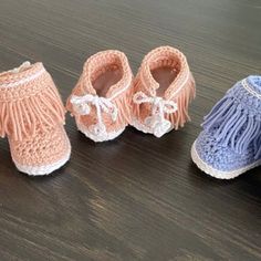 three pairs of crocheted baby shoes sitting on a wooden table next to each other