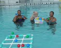 three women are in the pool with balls and a foosball board on it