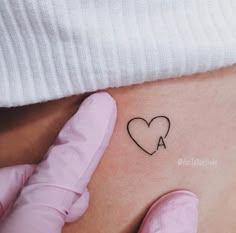 a woman's stomach with a small heart tattoo on the side of her belly