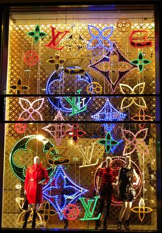 a window display with mannequins in front of it and christmas lights behind them