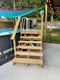 a wooden staircase next to an above ground swimming pool in a backyard with a blue tarp over it