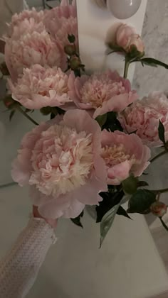 a bouquet of pink flowers sitting on top of a bathroom counter next to a mirror