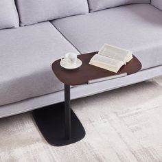 a coffee table with a book and cup on it next to a gray sectional couch