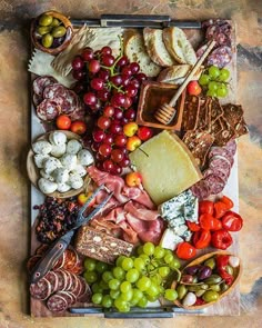 an assortment of cheeses, meats and vegetables on a platter