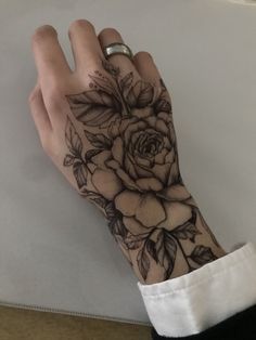 a woman's hand with a rose tattoo on her left arm and the wrist is covered in black ink