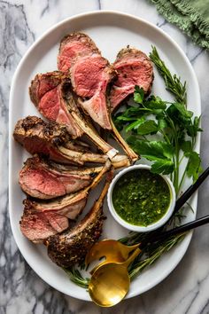 a plate with steak, greens and sauces on it next to some spoons