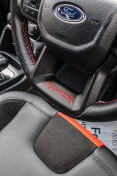 the interior of a car with black leather and red stitching on the steering wheel