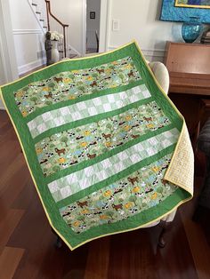 a green and white quilt sitting on top of a wooden floor next to a chair