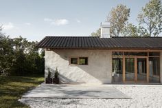 a white house with a black roof and two doors on the outside, surrounded by trees