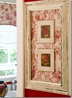 two framed pictures hanging on the wall in a kitchen with red walls and white trim