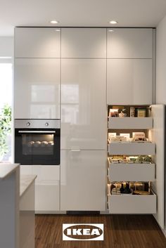 a kitchen with white cupboards and an oven in the center, surrounded by wood flooring