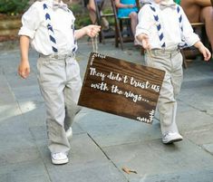 two young boys dressed in ties and holding a sign