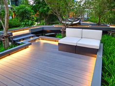 an outdoor seating area with couches and trees in the background at night, surrounded by greenery