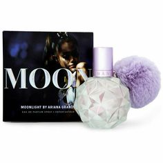 a bottle of moo perfume next to a box with a purple pom - pom