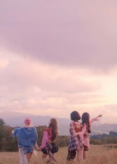 three girls are flying a kite in a field