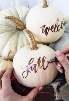 two white pumpkins with the words welcome fall painted on them