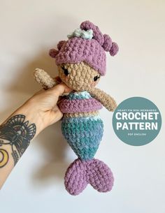 a crocheted mermaid doll is held up in the air by someone's hand