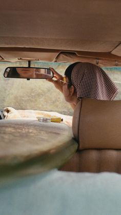 a woman sitting in the back seat of a car looking at her cell phone and taking a selfie