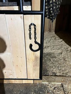 an open door with a black chain hanging from it's side and a wooden fence in the background