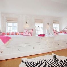 a zebra rug is on the floor in front of a white bed with pink pillows