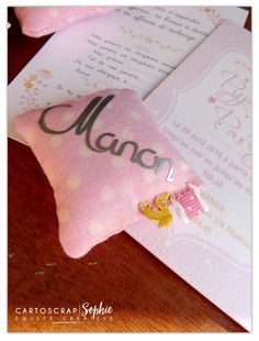 a close up of a pink pillow on top of a wooden table next to an envelope