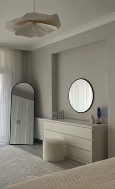 a bedroom with white furniture and round mirrors