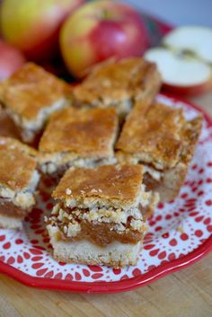 several pieces of apple pie on a red and white plate with apples in the background