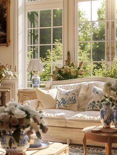 a living room filled with lots of furniture and flowers in vases on the coffee table