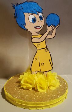 a paper cut out of a cartoon character holding a blue ball and wearing a yellow dress