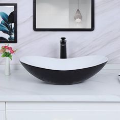 there is a black and white bowl sink on the counter in front of two framed pictures